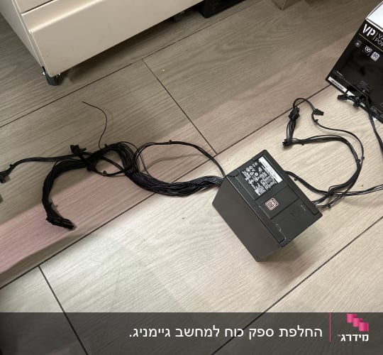 ספק כוח למחשב עם כבלים שחורים על הרצפה